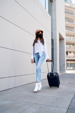 Dışarıda bavul taşıyan genç bir kadın..