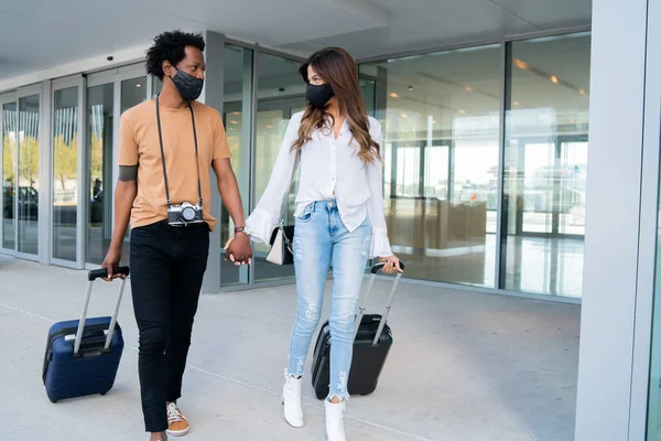 Pareja turística llevando maleta mientras camina al aire libre. — Foto de Stock