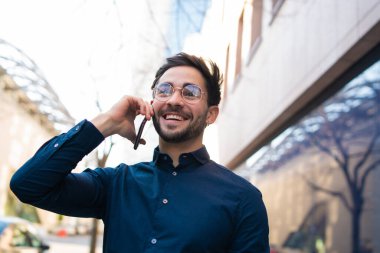 Genç adam dışarıda telefonla konuşuyor..