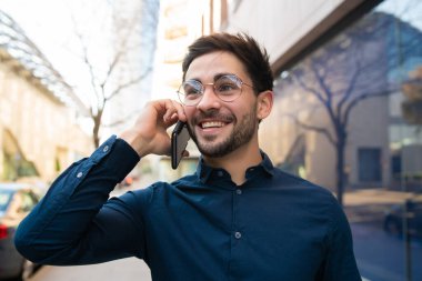 Genç adam dışarıda telefonla konuşuyor..