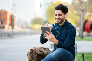 Genç adam dışarıda dijital tabletle video görüşmesi yapıyor..