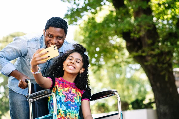 Flicka i rullstol och hennes pappa tar en selfie med telefon. — Stockfoto