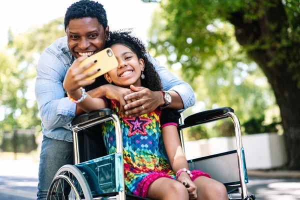 Flicka i rullstol och hennes pappa tar en selfie med telefon. — Stockfoto