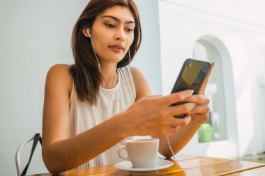 Kahve dükkanında telefon kullanan genç Latin kadın..