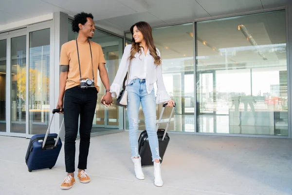 Pareja turística llevando maleta mientras camina al aire libre. — Foto de Stock