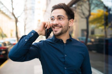 Genç adam dışarıda telefonla konuşuyor..