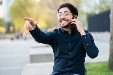 Genç adam dışarıda telefonla konuşuyor..