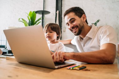 Bir baba evdeki online okulda oğluna yardım ediyor..