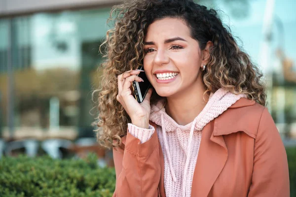Λατίνα γυναίκα χαμογελά ενώ μιλάμε στο τηλέφωνο σε εξωτερικούς χώρους στο δρόμο. — Φωτογραφία Αρχείου