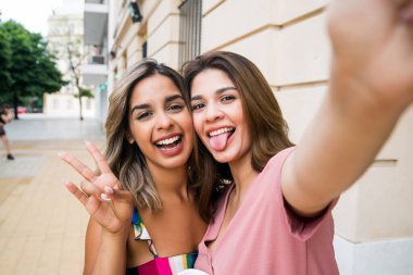 İki arkadaş dışarıda selfie çekiyor..