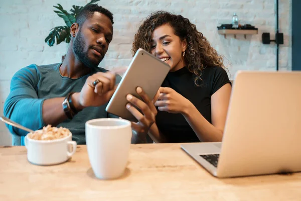 Coppia che utilizza un tablet digitale e un computer portatile mentre fa colazione. — Foto Stock