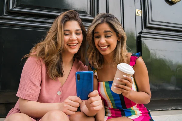 Dois amigos usando telefone celular ao ar livre. — Fotografia de Stock