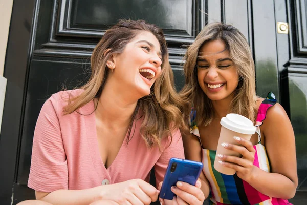 Dois amigos usando telefone celular ao ar livre. — Fotografia de Stock