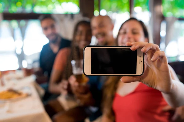 バーで携帯電話で自撮りしている友人のグループ. — ストック写真