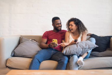 Çift evdeki koltukta otururken cep telefonu kullanıyor..