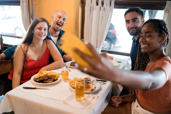 Gruppo di amici che si fanno un selfie con un cellulare in un ristorante. — Foto Stock