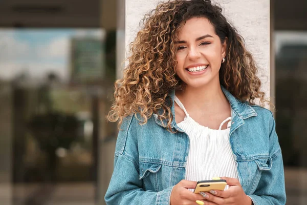 Mujer latina usando un teléfono móvil mientras camina al aire libre en la calle. —  Fotos de Stock