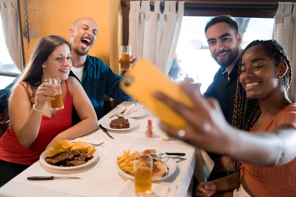 Gruppo di amici che si fanno un selfie con un cellulare in un ristorante. — Foto Stock