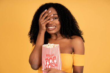 Afro kadın film izliyor ve patlamış mısır yiyor..
