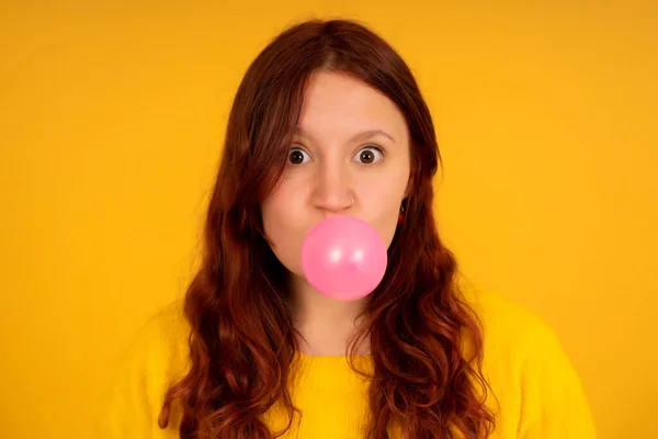 Mujer joven haciendo un globo con la goma de mascar. — Foto de Stock