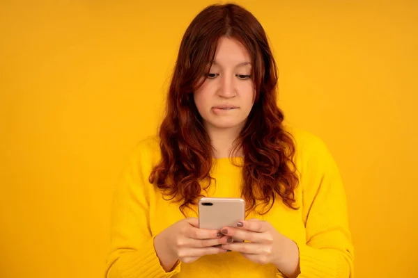 Mujer con una expresión preocupada en su cara mientras usa un teléfono móvil. —  Fotos de Stock