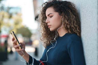 Sokakta cep telefonunu kullanan genç bir kadın..