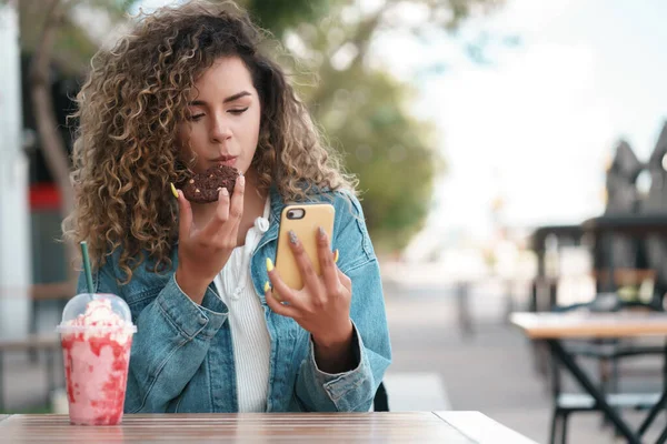 Mujer latina usando un teléfono móvil mientras está sentada en una cafetería. —  Fotos de Stock