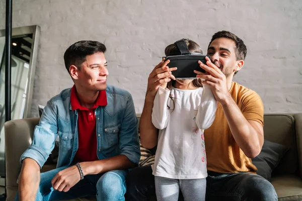 Niña jugando videojuegos con sus padres en casa. Imagen De Stock