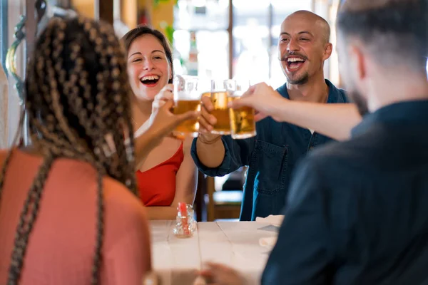 Grupo de amigos brindam com copos de cerveja em um restaurante. — Fotografia de Stock