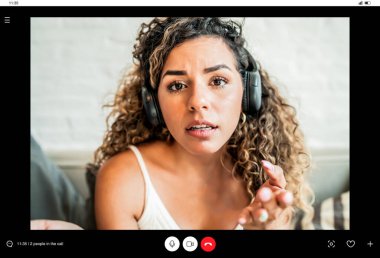 İş yerinde çalışan genç bir iş kadını evde otururken görüntülü arama yapıyor..