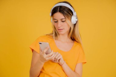 Cep telefonu ve kulaklık kullanan genç bir kadın..