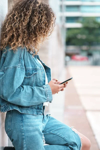 Young woman using her mobile phone outdoors on the street.