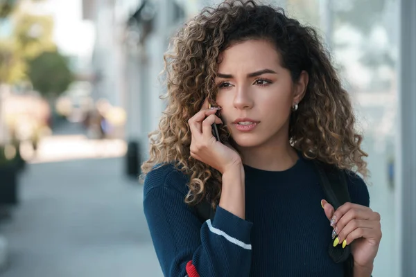 Donna latina che parla al telefono all'aperto per strada. Foto Stock