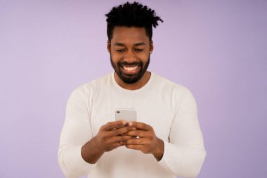 Cep telefonuna bakarken gülümseyen bir afro adam..