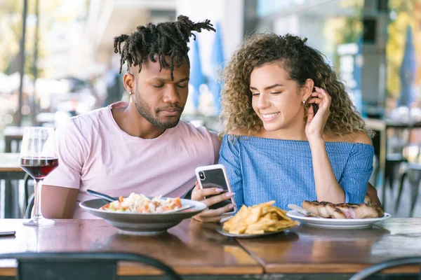 Paar benutzt Handy bei einem Date in einem Restaurant. — Stockfoto