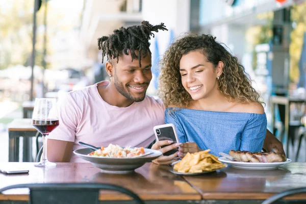 Paar benutzt Mobiltelefon in Restaurant. — Stockfoto