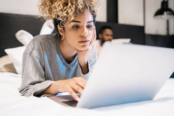 Donna che utilizza un computer portatile mentre sdraiato sul letto con il fidanzato. — Foto Stock