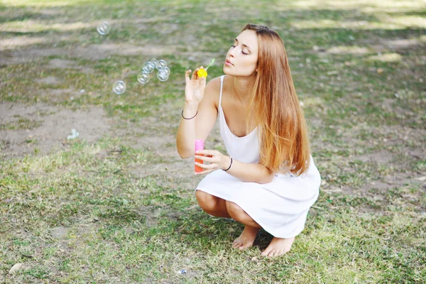 Jovem mulher soprando bolhas de sabão no ar . — Fotografia de Stock