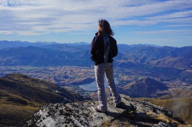 Güzel manzaranın tadını çıkarmak için zirvede yürüyüş yapan bir kız.