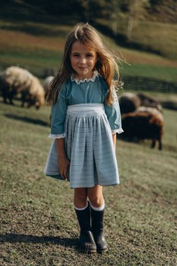 Kırsalda mavi bir bohem elbisesi içinde yürüyen sevimli küçük kız. 