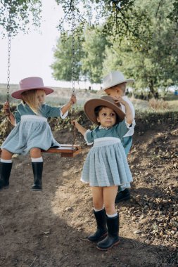 Güzel küçük kız salıncakta sallanıyor kırsalda bir ağaçta ve arkadaşları dolaşıyor 