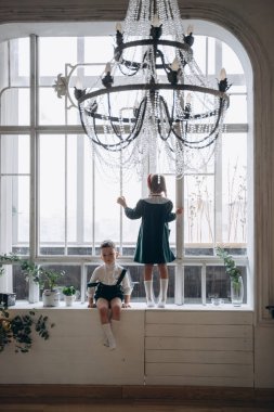 Bohem yeşil elbiseli güzel bir kız. Pencerede ağabeyiyle oturuyor. Noel süsleriyle dolu bir odada.