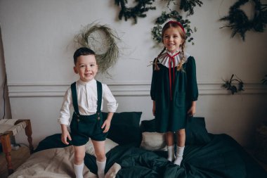 Bohem gibi giyinmiş güzel çocuklar kanepede oturur ve Noel süsleriyle dolu bir odada oynaşırlar.