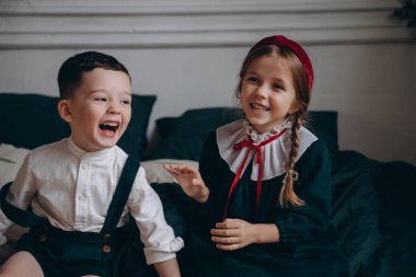 Bohem gibi giyinmiş güzel çocuklar kanepede oturur ve Noel süsleriyle dolu bir odada oynaşırlar.