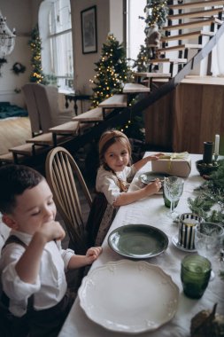 Noel masasında oturan şenlikli elbiseli güzel çocuklar