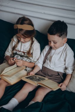 Bohem gibi giyinmiş güzel çocuklar kanepede oturup Noel süsleriyle dolu bir odada kitap okuyorlar.