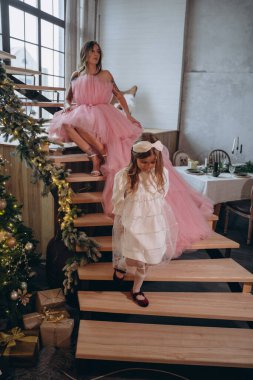 Peçeli güzel bir kadın yeni pembe elbiseli küçük bir kız ve kameraya poz veriyor.