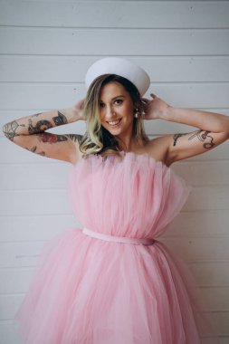 Stüdyoda poz veren pembe kısa ve kabarık elbiseli güzel bir kadın.