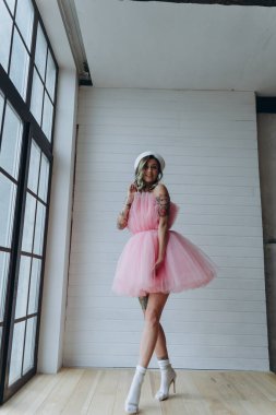 Stüdyoda poz veren pembe kısa ve kabarık elbiseli güzel bir kadın.