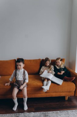 Bohem gibi giyinmiş güzel çocuklar Noel arifesinde kanepede oturup pencerenin yanında kitap okuyorlar.